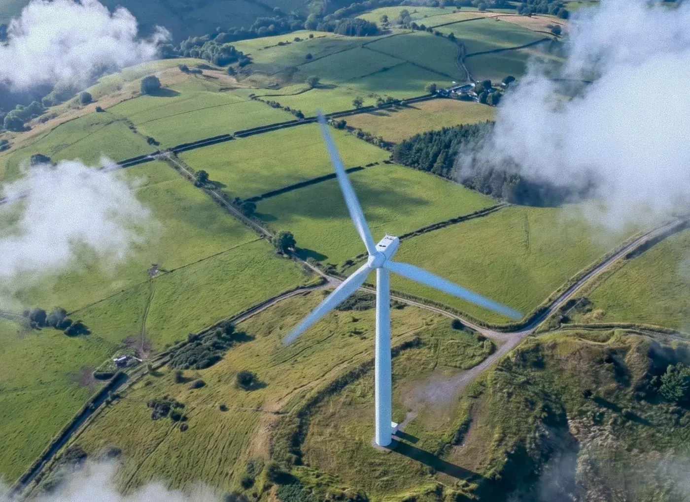 Aerial view of a wind turbine over green farmland